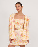 Top floral en lino con escote recto combinado con short y blazer del set, look resort elegante vista frontal