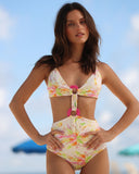 Modelo usando el vestido de baño entero Gioia di Sole en estampado floral marfil con detalles de argollas rosas, vista frontal.